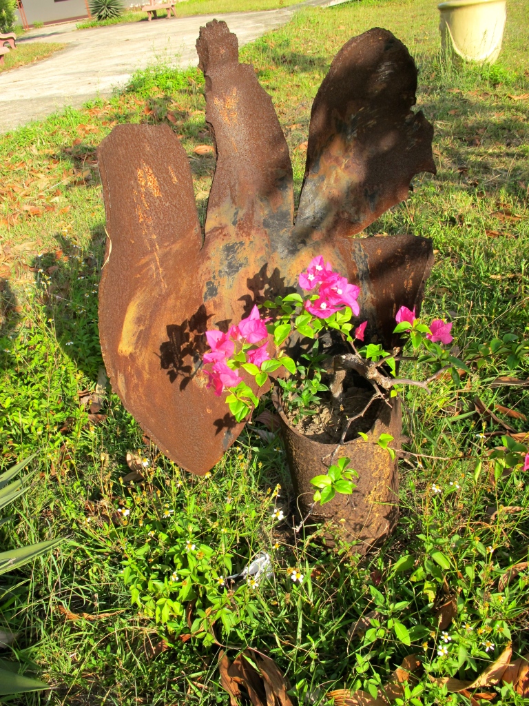 A discarded UXO is used as a flower pot in the garden outside of the Project Renew office. (Photo by Nissa Rhee, June 2014).